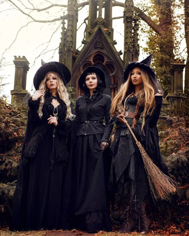 three women dressed as witches standing in front of a building