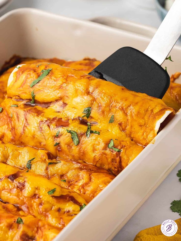 a casserole dish with cheese and meat in it is being held by a spatula