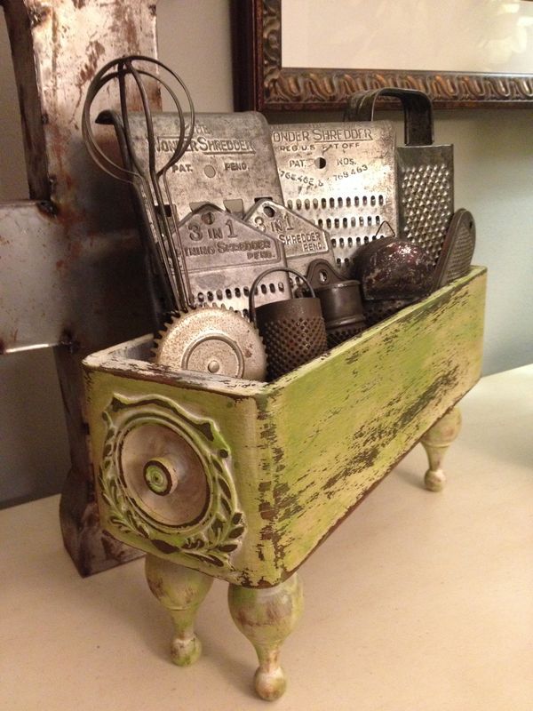 an old wooden box filled with assorted kitchen utensils on a table next to a mirror