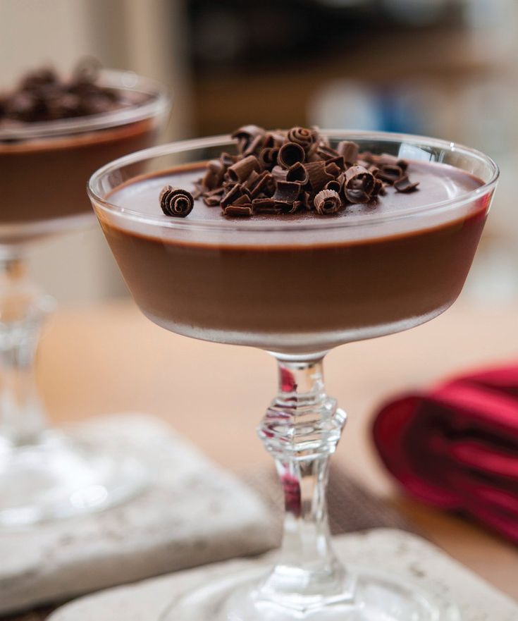 two glasses filled with chocolate pudding on top of a table