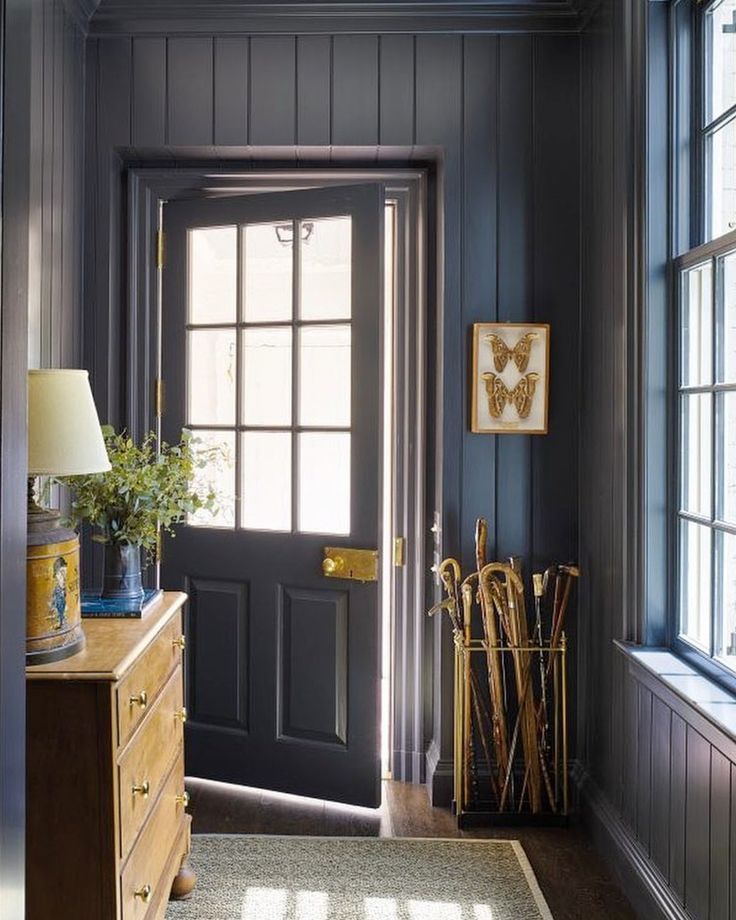 an entryway with dark wood paneling and blue walls