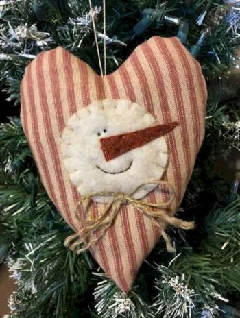 a heart shaped ornament hanging from a christmas tree with a smiling face on it