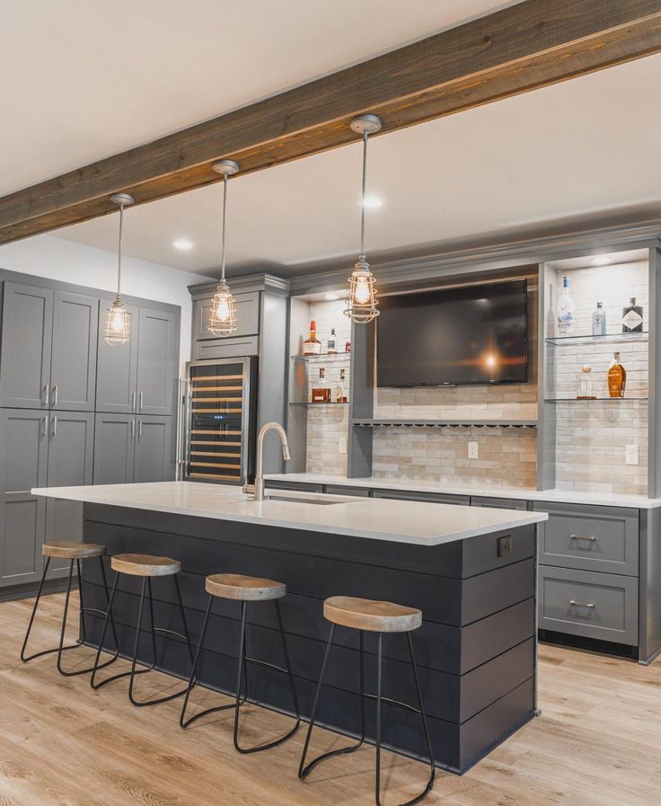 a kitchen with an island and bar stools in the center, surrounded by gray cabinets