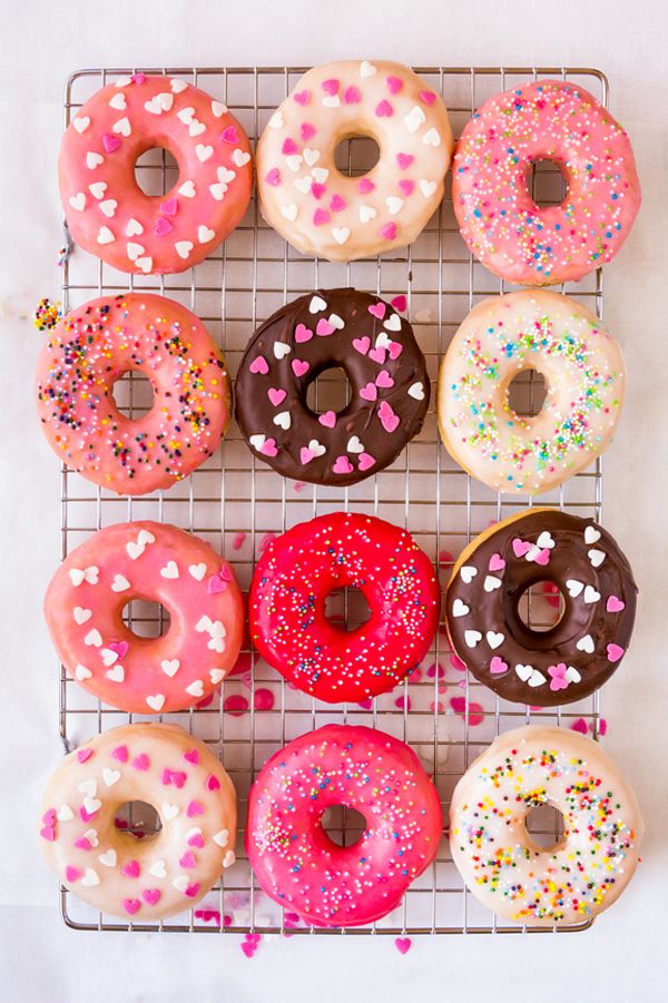 six doughnuts on a cooling rack with sprinkles and chocolate frosting