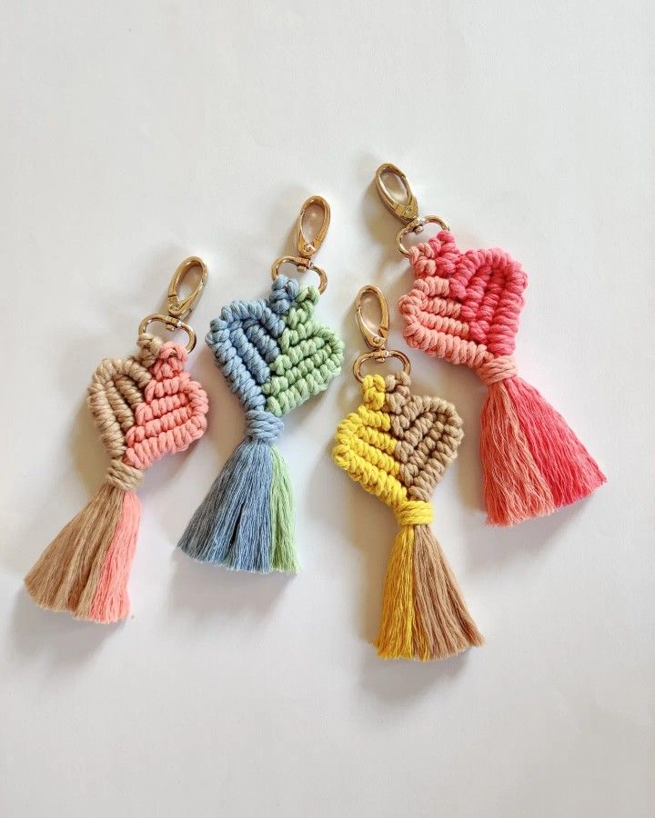 four tasselled keychains with different colors and designs on them sitting on a white surface