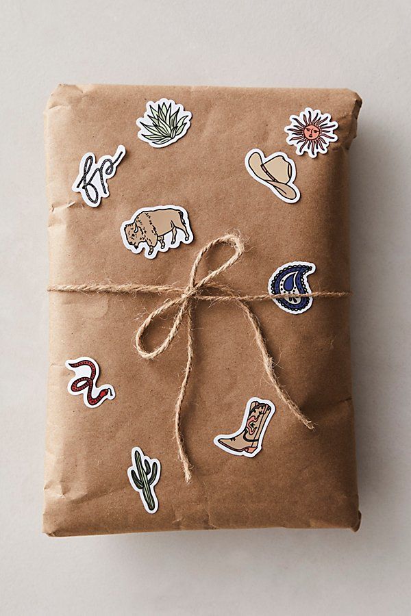 a wrapped gift with stickers on it sitting on a white table next to a brown wrapping paper