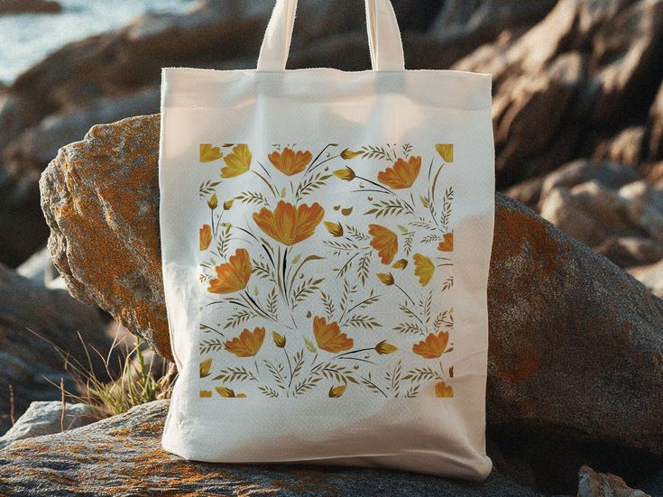 a tote bag sitting on top of a rock next to the ocean and rocks