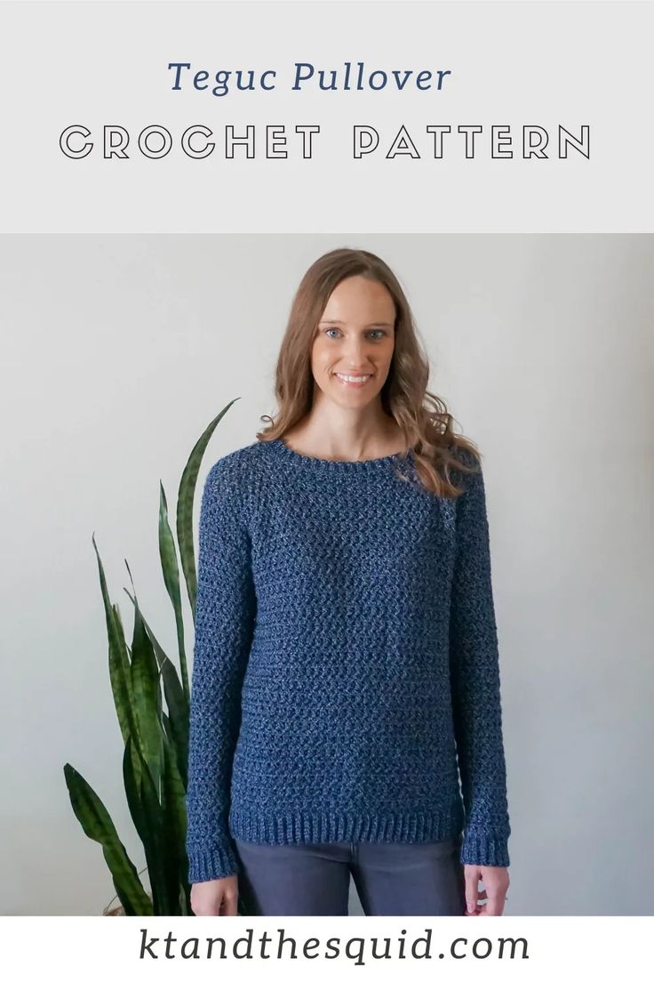 a woman standing in front of a plant wearing a blue sweater