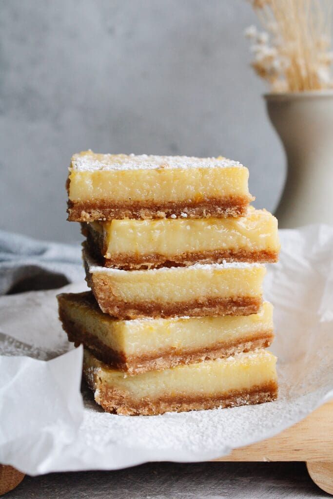 four pieces of cake sitting on top of paper next to a wooden spoon and vase