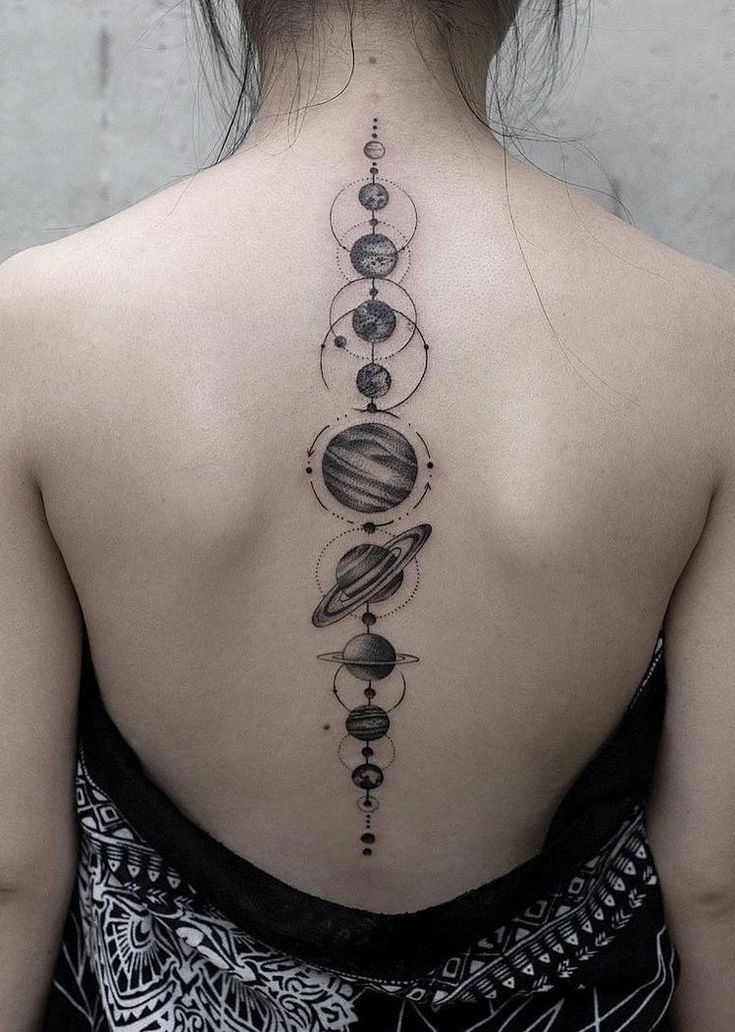 the back of a woman's neck with planets on it