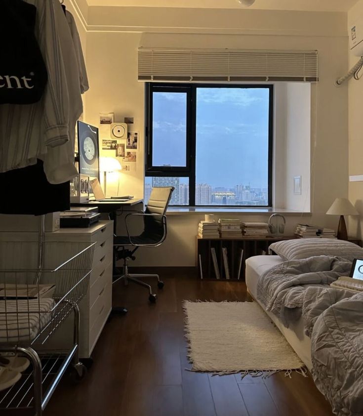 a bedroom with two beds, a desk and a large window overlooking the city below