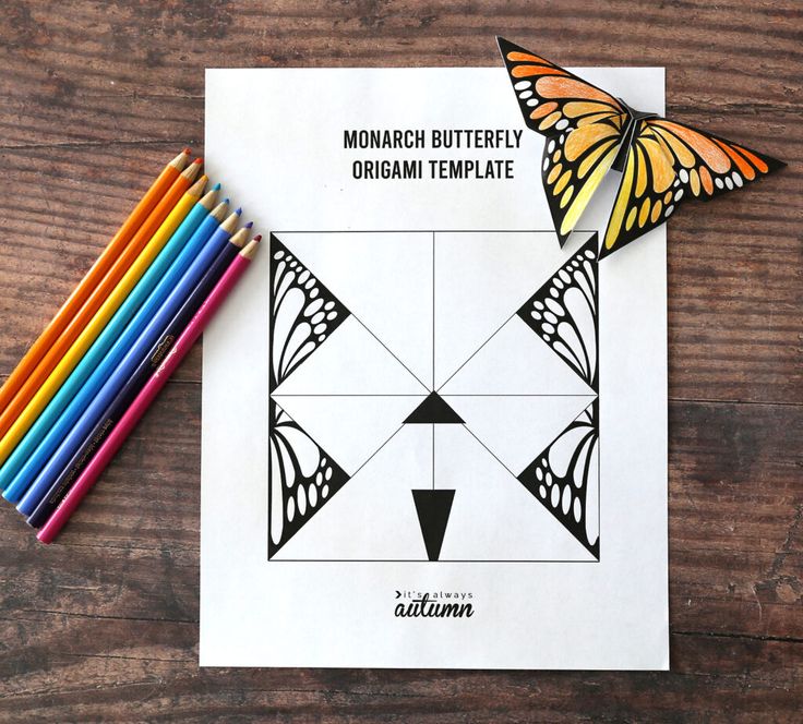 the monarch butterfly origami template is next to colored pencils on a wooden table