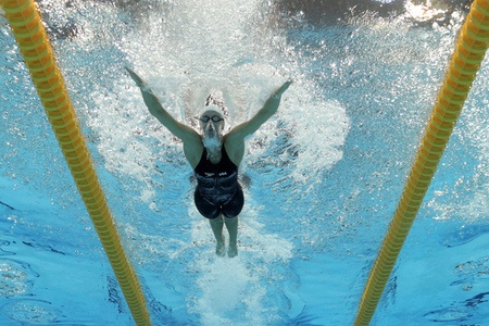 a woman swimming in the pool with her hands up and head above the water's surface