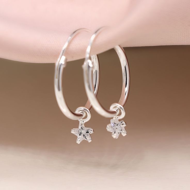 A stunning pair of sterling silver huggie hoop sleeper earrings with a loose twinkling cubic zirconia star charm that sparkles in every light Guaranteed to add a touch of sparkle to any look, our huggie hoop earrings with their tiny star charm are crafted from the finest sterling silver with a classic hinged fastening and are suitable for almost any age. A lovely Christmas gift, stocking filler or for a birthday treat. These sweet huggies are perfect for everyday with a really simple design when Sterling Silver Star Charm Huggie Earrings, Sterling Silver Hoop Earrings With Star Charm For Gift, Silver Star-shaped Huggie Earrings For Gifts, Silver Star Shaped Huggie Earrings For Gift, Silver Hoop Earrings With Star Charm As Gift, Minimalist Sterling Silver Hoop Earrings With Star Charm, Sterling Silver Huggie Earrings With Star Charm For Everyday, Silver Huggie Earrings With Star Charm For Gift, Silver Huggie Earrings With Star Charm As Gift