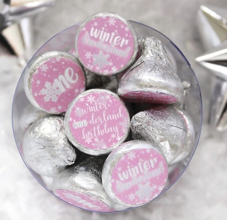 a glass bowl filled with pink and silver foiled candies that says winter wonderland