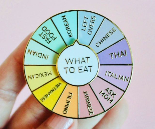 a hand holding a colorful wheel of fortune with words on the side that spell out what to eat