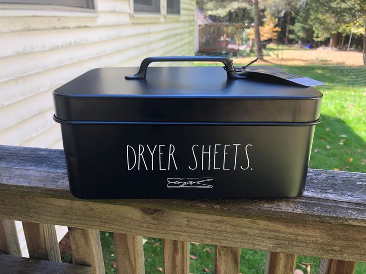 a black metal box sitting on top of a wooden rail next to a house and yard