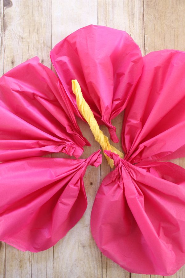 pink paper flowers with yellow stems in the center on a wooden surface, ready to be used as decorations