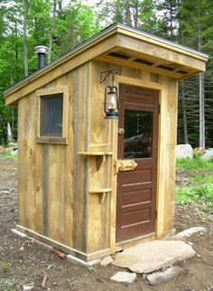 a small wooden outhouse in the woods