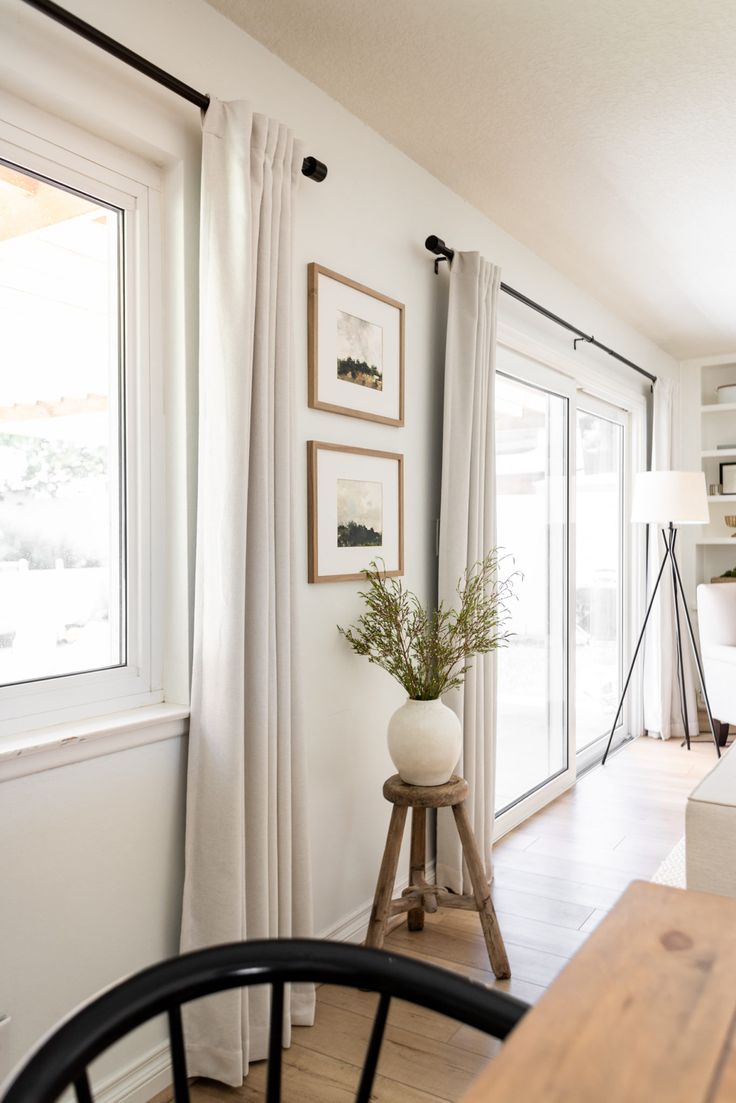 a living room filled with furniture and a wooden table next to a window covered in white curtains