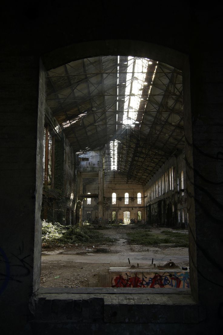 an abandoned building with lots of windows and graffiti on the walls is seen through a doorway