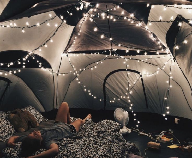 a person laying in a bed inside of a tent with lights on the ceiling and walls