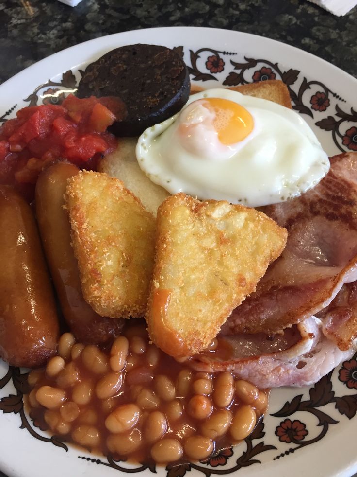 an english breakfast on a plate with beans and eggs