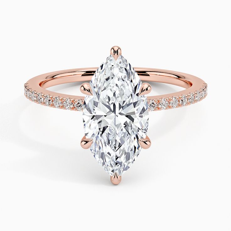 a rose gold engagement ring with a pear shaped diamond in the center and pave set shoulders