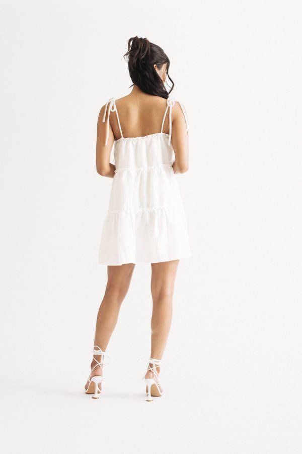 "Take Your Style Up A Notch With This Spring Fling Off White Tiered Babydoll Mini Dress. The Tiered Skirt And Ruffled Trim Add A Touch Of Fun And Flirty Vibes, While The Adjustable Tie Straps Provide A Comfortable And Custom Fit. Made From A Soft And Flowy Fabric, This Dress Is Perfect For A Day Out Or A Day In. Add Some Strappy Sandals Or Some Sneakers And You'Re Good To Go!" Babydoll Mini Dress, Flowy Fabric, Spring Fling, Tiered Skirt, Strappy Sandals, Custom Fit, Baby Dolls, White Dress, Off White