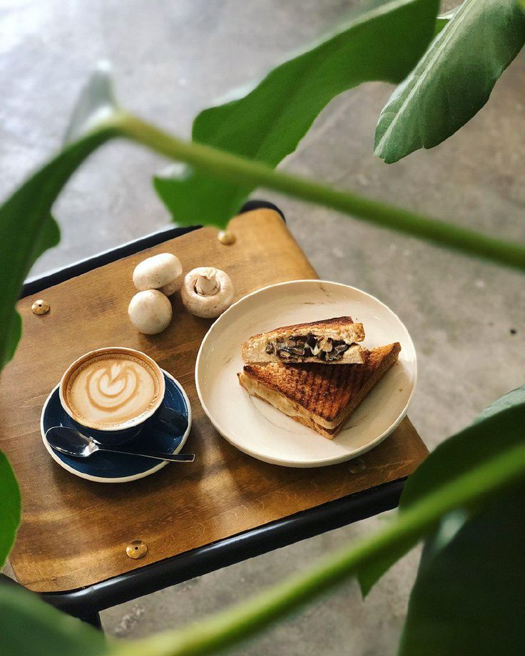 a plate with some food on it next to a cup of cappuccino