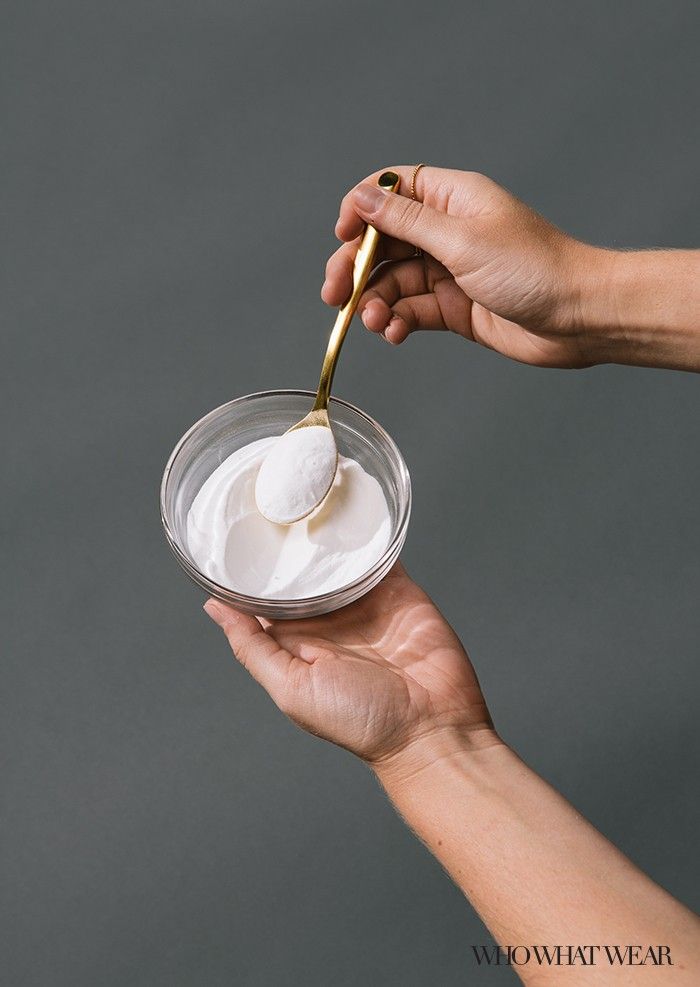 two hands holding a small bowl with whipped cream on it and gold spoon in the other hand