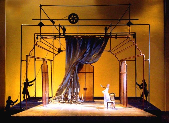 an image of a stage setting with people on the stage and one person sitting in a chair