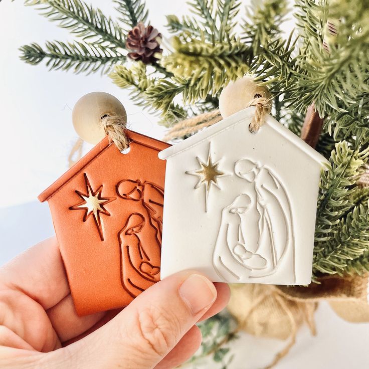 a hand holding a christmas ornament in front of a tree