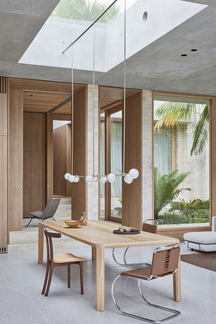 a dining room table and chairs in front of large windows