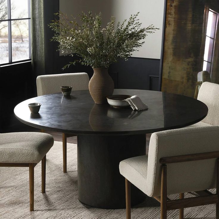 a round table with chairs around it and a vase filled with flowers in the center