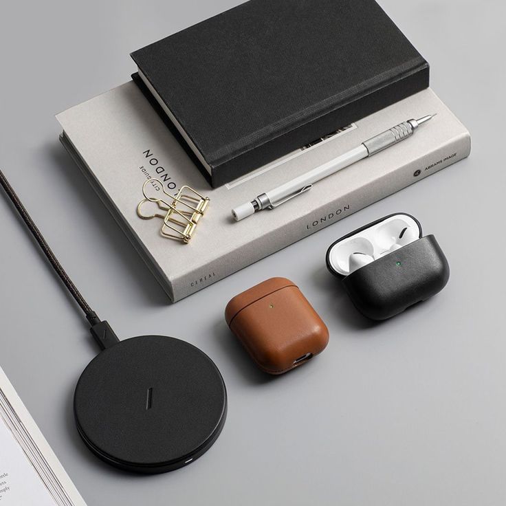 an assortment of electronic gadgets and accessories on a gray surface with a notepad