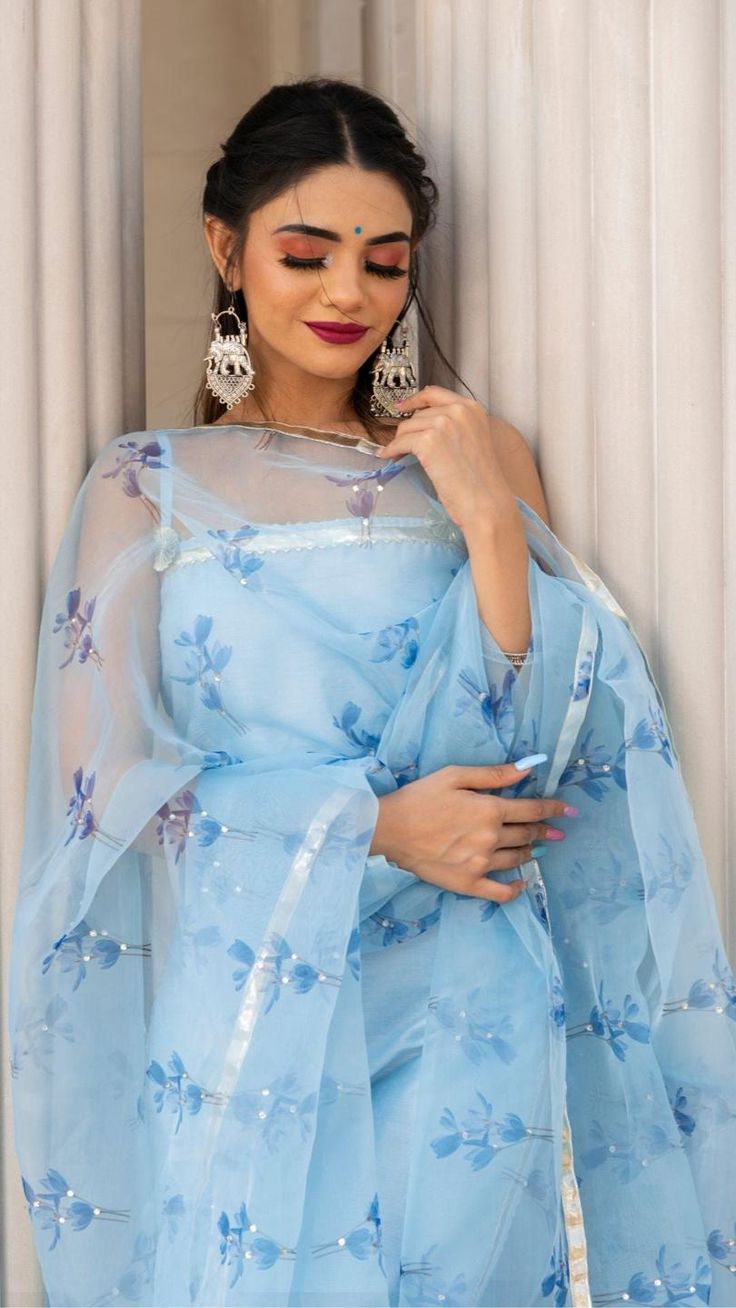 PRODUCT DESCRIPTION: Anarkali : Cotton silk Pant: Cotton silk LINING : Cotton Dupatta: Oragnza Color: CELESTE BLUE work : Gotta lace work, stone work embellishment all over dupatta No. Of Components : Set of 3 Wash Care : Dry Clean Customization : Only Size and Length Of Product SKU#: 11403072BL Disclaimer: All our pieces are handcrafted in our manufacturing unit .We Ensure that our pieces are shot professionally under controlled lighting. Colours tend to be perceived differently depending on fa Transitional Organza Salwar Kameez With Cutdana Details, Festive Organza Salwar Kameez With Unstitched Blouse, Unstitched Blue Chinon Blouse Piece, Blue Chinon Blouse Piece For Navratri, Unstitched Bollywood Style Light Blue Salwar Kameez, Unstitched Bollywood Salwar Kameez In Light Blue, Blue Georgette Blouse Piece With Dupatta, Blue Georgette Dupatta With Pallu, Blue Chinon Churidar For Party