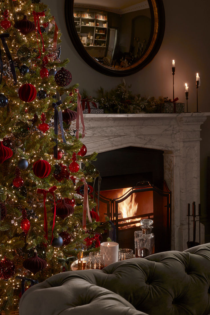 a decorated christmas tree in front of a fireplace