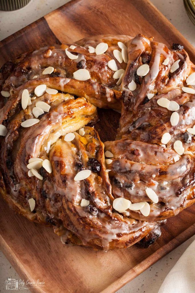 a cinnamon bundt cake with almonds and icing on a wooden cutting board