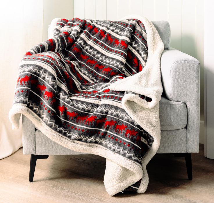 a couch with a blanket on top of it next to a chair and white wall