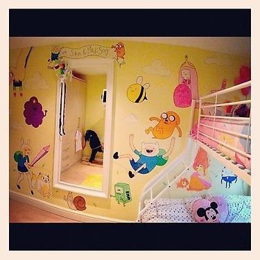 a child's bedroom with yellow walls and cartoon wall decals on the walls