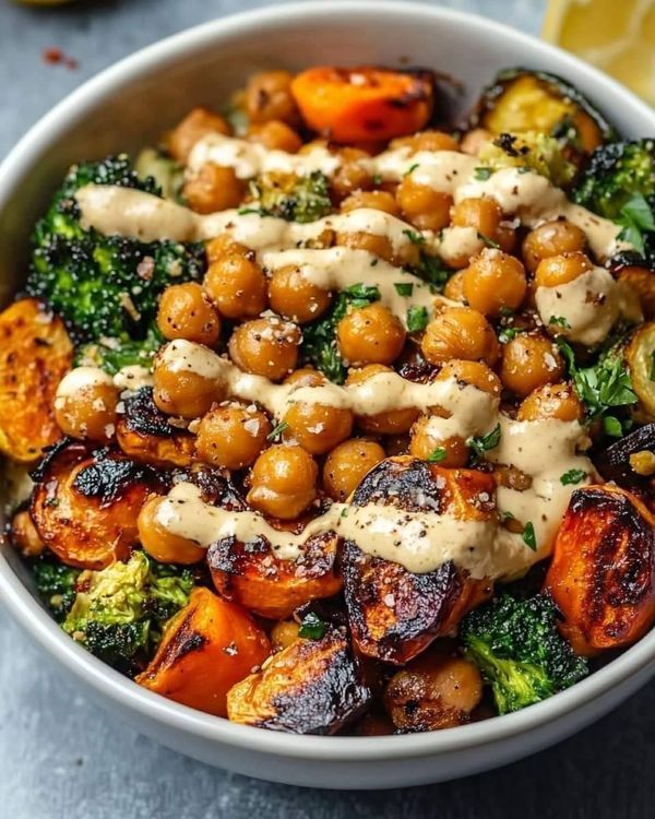 a white bowl filled with broccoli, chickpeas and carrots covered in sauce