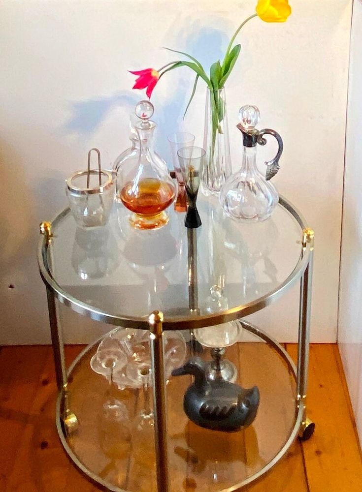 a glass table with some vases on top of it and flowers in the middle