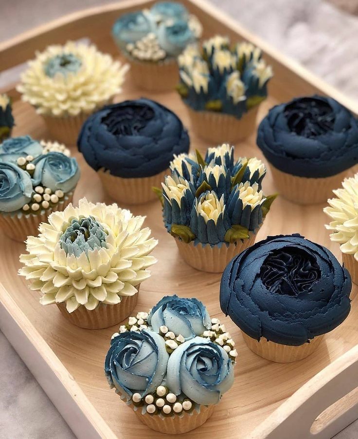 cupcakes decorated with blue and white flowers on a wooden tray