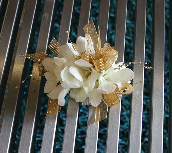 a white and gold boutonniere is sitting on a metal surface with blue background