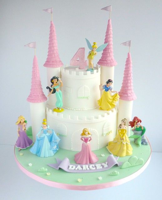 the cake is decorated with princesses and castle figurines on it's side