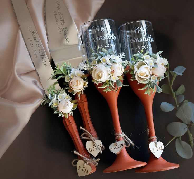 three wine glasses decorated with flowers and hearts are sitting on a table next to a ribbon