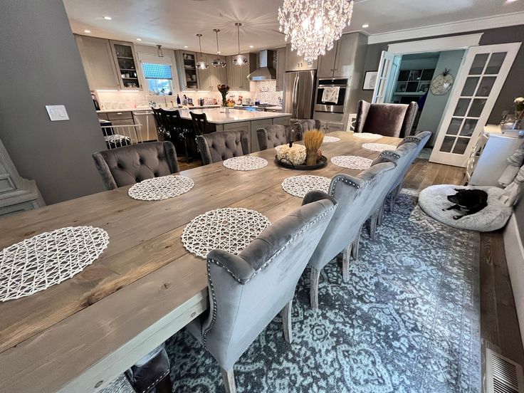 a dining room table with chairs and a chandelier hanging from the ceiling