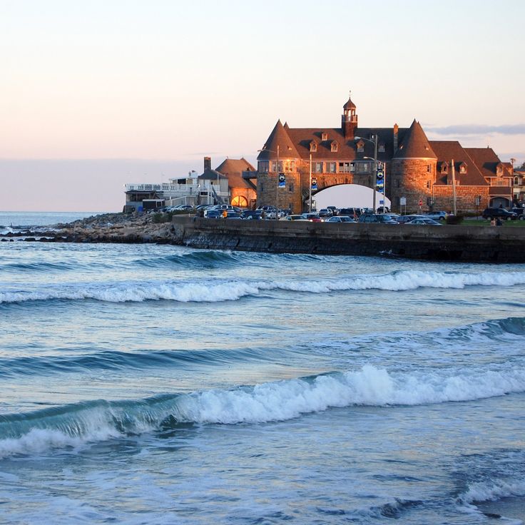 a large building sitting on top of a beach next to the ocean with waves in front of it