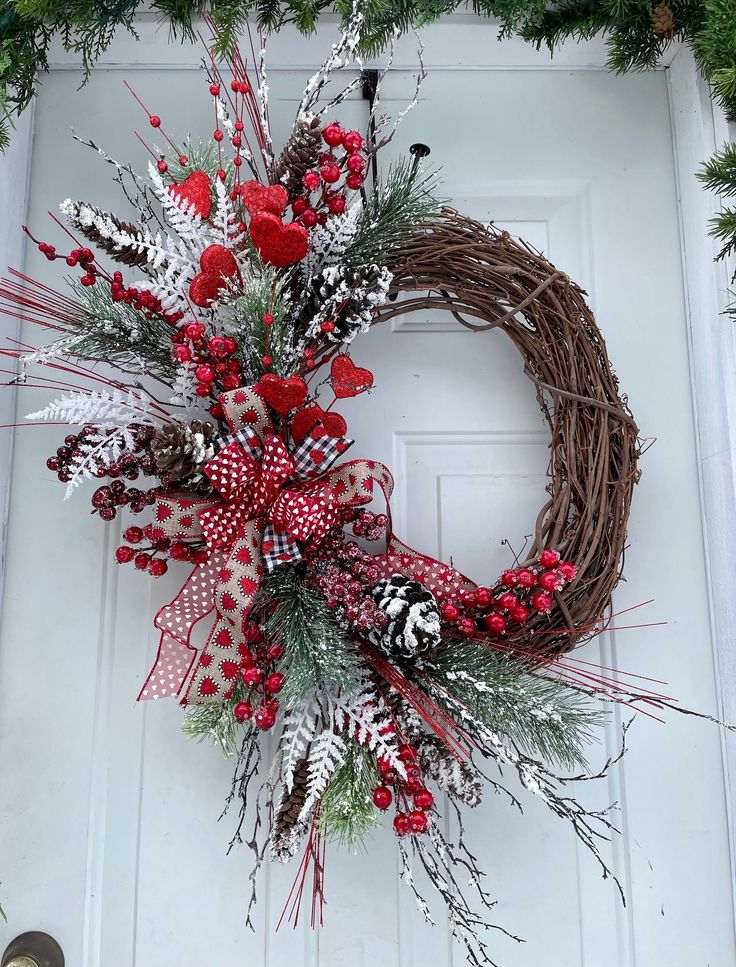 a wreath with red berries and pine cones on the front door